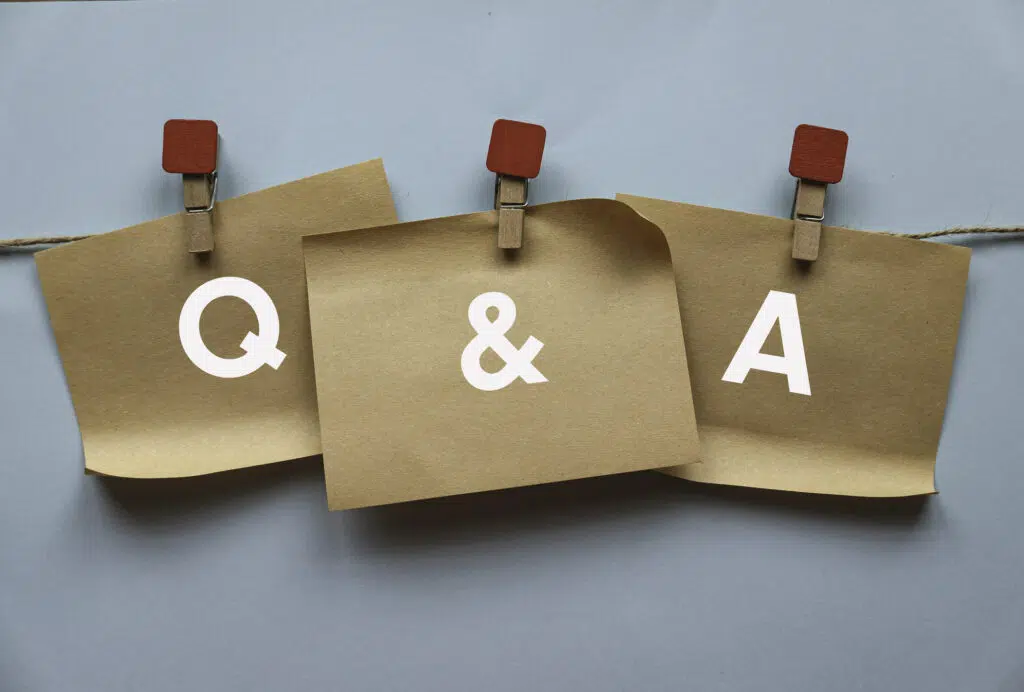 Three brown paper hanging on the rope written with letter Q, A and ampersand. Question and answer concept.