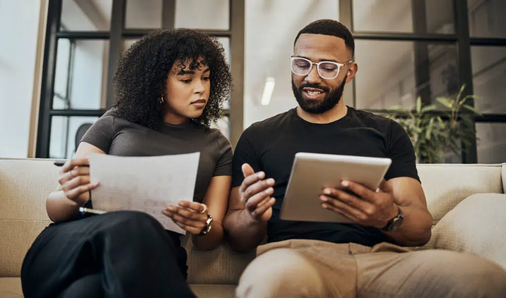 Tablet, documents and finance with a black couple in their home to manage savings, investment or budget. Money, paper and accounting with a man and woman planning for financial growth in their investment